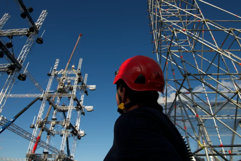 Rigger mit rotem Helm vor Traversenturm